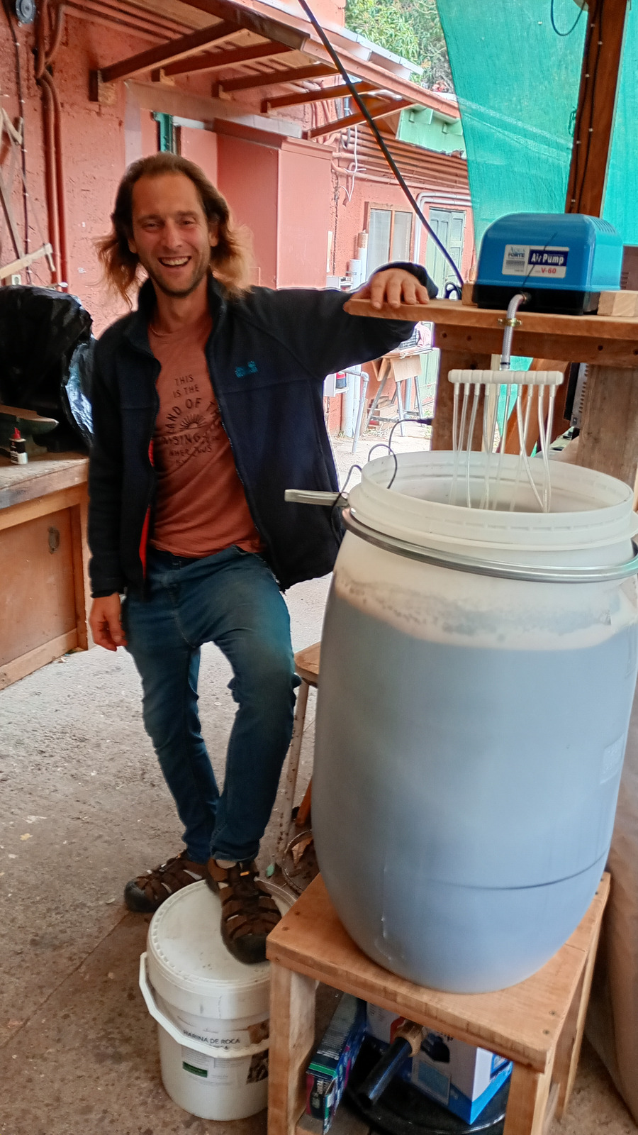 Alexander Maier neben einem belüfteten Kompost-Tee-Ansatz mit Luftpumpe und Belüftungssystem